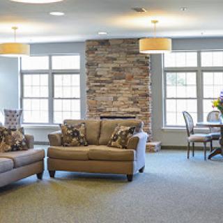 A cozy living room setup featuring comfortable couches, a dining area, and natural light from large windows.