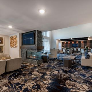 A modern lounge area featuring comfortable seating, a central fireplace, and a television.