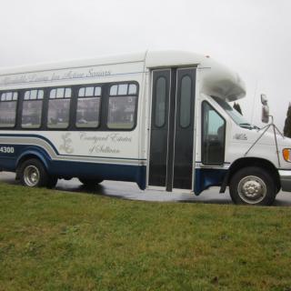 A white and blue bus parked on a grassy area.