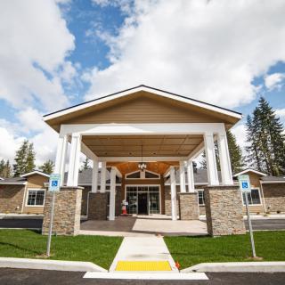 A building with a prominent entrance featuring columns and a peaked roof under a partly cloudy sky.