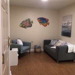 A cozy living room with a sofa and armchair, featuring wall art and wooden flooring.