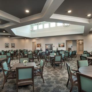A spacious dining area with neatly arranged tables and chairs under warm lighting.