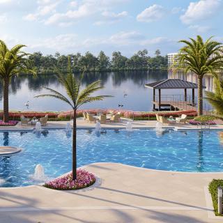 A luxurious poolside view overlooking a serene lake with palm trees and a gazebo.