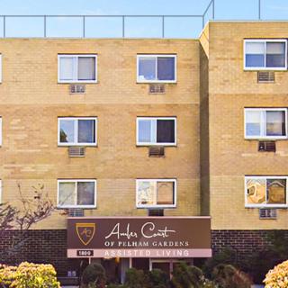 A view of a multi-story residential apartment building with several windows and a sign at the entrance.