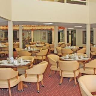 An empty restaurant dining area with neatly arranged tables and chairs on a carpeted floor.