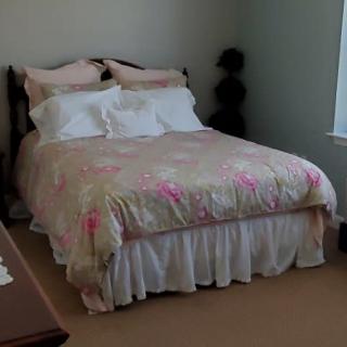 A cozy bedroom with a neatly made bed and floral bedding.