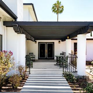 A welcoming entrance featuring a modern design with shaded seating and lush landscaping.