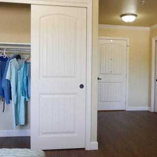 A bedroom with an open closet showing clothes hanging inside.