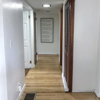 A hallway with wooden flooring and white walls, featuring multiple doors.