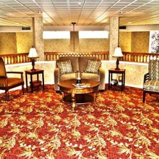 A hotel lobby with a seating area, featuring patterned carpet and elegant furniture.