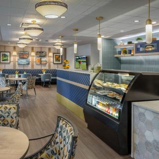 A stylish and modern cafe interior with comfortable seating and a display case filled with treats.