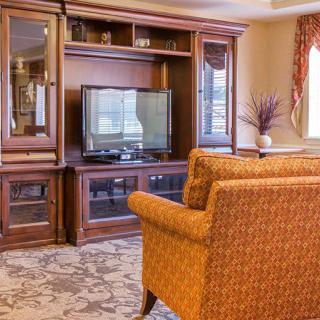 A cozy living room with a wooden entertainment center and comfortable chairs.