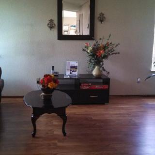 A cozy living room with a central table, decorative flowers, and a wall-mounted mirror.