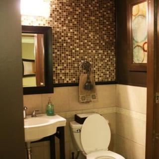 A cozy bathroom featuring mosaic tile walls, a sink with a mirror, and a toilet.