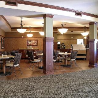 A cozy restaurant dining area with tables and chairs arranged neatly, featuring warm lighting and elegant decor.