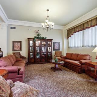 A classic-style living room featuring comfortable sofas, a decorative cabinet, and a chandelier.