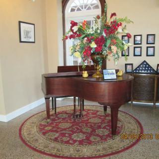 A grand piano adorned with flowers in a well-decorated room.