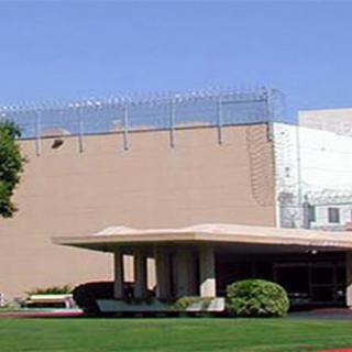 A secure facility with barbed wire fencing and surrounding greenery.