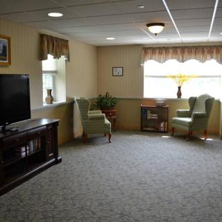 A cozy living room with a television, seating area, and large window.