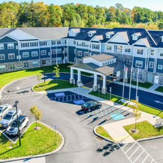Aerial view of a large residential or commercial building with a parking lot and landscaped grounds.