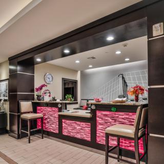 A modern reception area featuring a sleek desk with illuminated panels, comfortable chairs, and decorative floral arrangements.