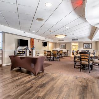 A spacious dining area featuring wooden floors, tables, and chairs, complemented by ceiling lights and two televisions.