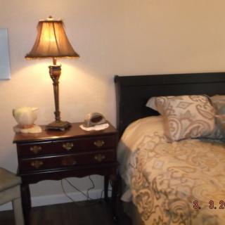 A cozy bedroom with a bedside table and lamp next to a neatly made bed.