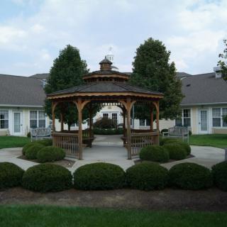 A charming gazebo surrounded by manicured bushes and trees in a landscaped garden.