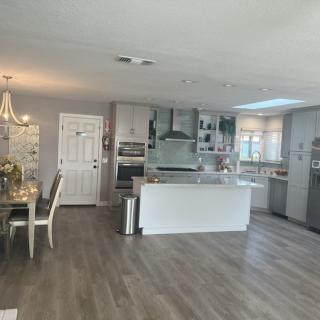 A modern open-plan kitchen and dining area with sleek white cabinetry and hardwood flooring.