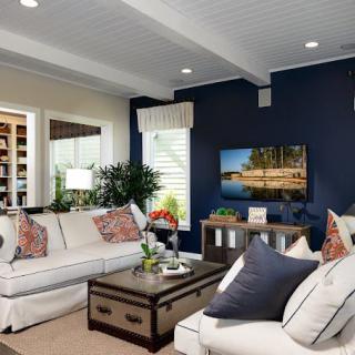 A stylish and comfortable living room with modern decor, featuring a navy accent wall, white sofas, and a well-placed coffee table.