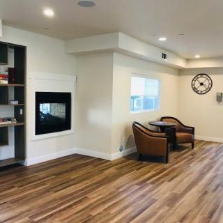 A modern living room with wooden flooring, featuring a fireplace and a cozy seating area.
