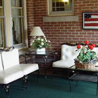 A cozy seating area featuring white upholstered furniture, a glass table, and decorative plants, complemented by an American flag wall art.