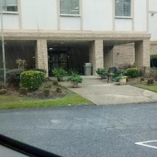 A view of the entrance to a building with landscaped greenery and a pathway.