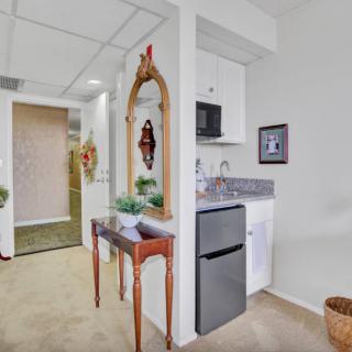 A small hallway featuring a decorative mirror and console table next to a kitchenette with a mini fridge and microwave.