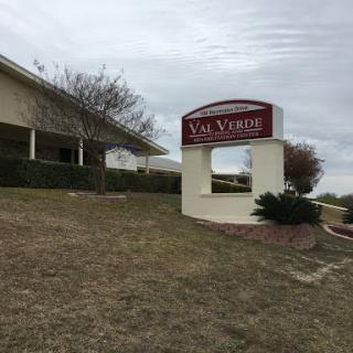 A sign indicating the Val Verde location, set against a cloudy sky.