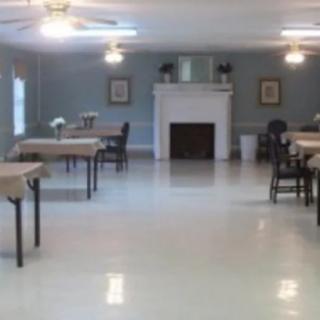 A spacious room with tables and chairs, featuring a fireplace and ceiling fans.