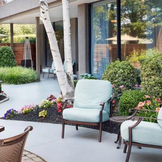 A serene patio featuring comfortable outdoor chairs surrounded by lush garden landscaping.