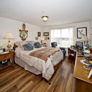 Cozy bedroom with a large bed, wooden flooring, and various decorative elements.