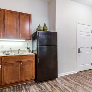 A compact kitchen area with wooden cabinets and a black refrigerator.