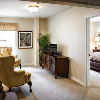 A cozy living room with elegant armchairs, a console table with a TV, and ample natural light.