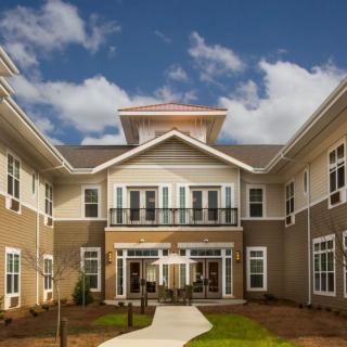 Exterior view of a modern residential building under a blue sky with clouds.