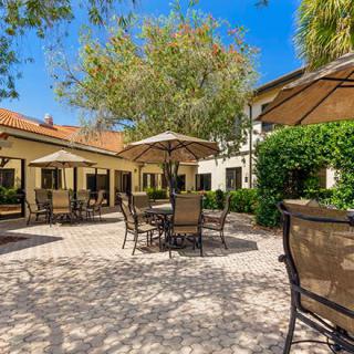 A charming patio area with tables, chairs, and umbrellas under a sunny sky.