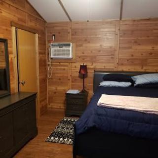 Cozy wooden bedroom with a bed, dresser, and air conditioner.