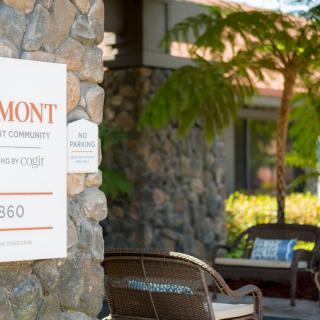 A stone wall with a sign and outdoor seating area.