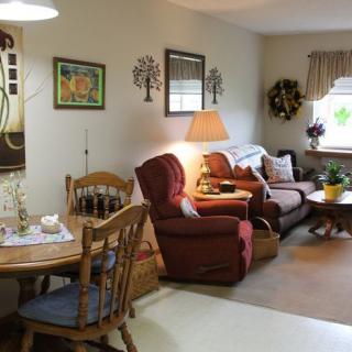 A cozy living room with a sofa and armchair, adjacent to a dining area.