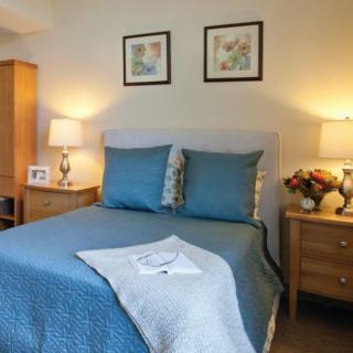 A cozy bedroom with a neatly made bed, flanked by bedside tables and warm lighting.