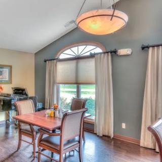 A cozy dining room with a wooden table, chairs, and a large window adorned with curtains.
