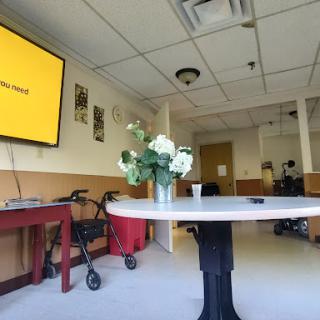 A spacious interior room featuring a table with flowers, a television on the wall, and wheelchair accessibility.