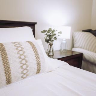 A cozy and elegantly designed bedroom with a neatly made bed and stylish decor.