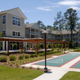 A modern apartment complex with well-maintained landscaping and an outdoor court.